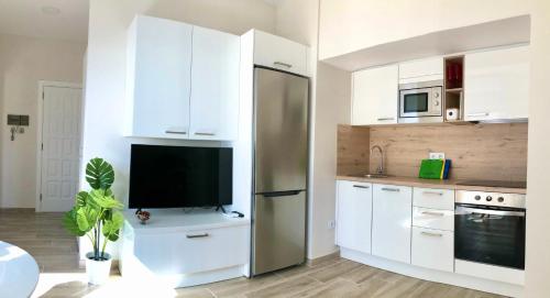 a kitchen with a refrigerator and a tv on a counter at Pequeño paraíso frente al mar Playa Chica in Santa Cruz de Tenerife