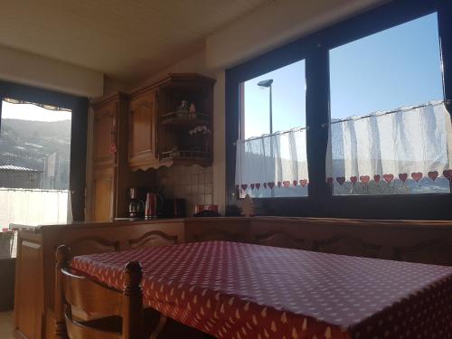 - une cuisine avec une table et 2 grandes fenêtres dans l'établissement La Pinéguette maison 12 personnes spa 6 pers décoration chalet sauna 4 pers, à La Bresse