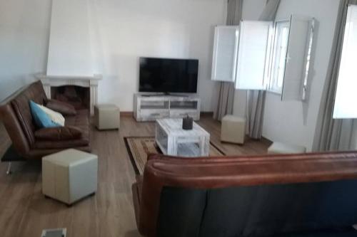 uma sala de estar com um sofá e uma televisão de ecrã plano em Vila Verde em Castro Marim