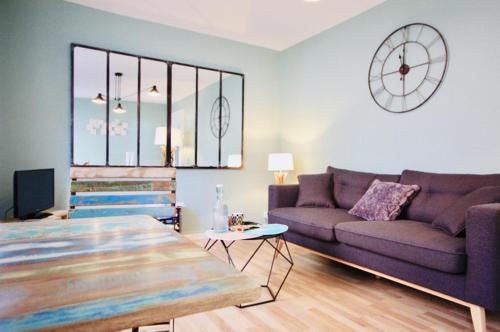 uma sala de estar com um sofá roxo e um relógio em #Private Scandinave Sweet House ! em Saint-Dizier