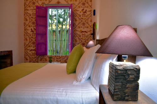 a bedroom with a bed with a lamp and a window at Tlaquepaque Pueblito in Guadalajara