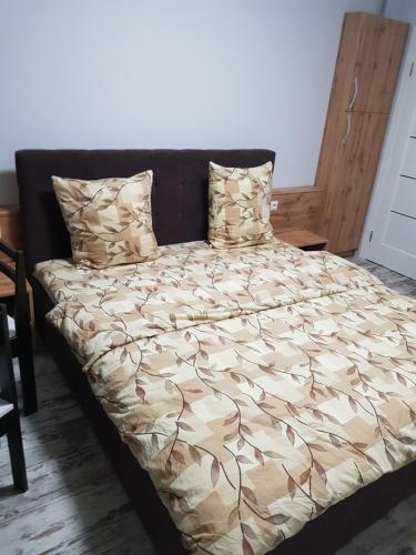 a bed with a brown comforter and pillows at Апарт-сервис в Ужгороде in Uzhhorod