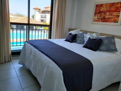 Condomínio Mediterranee في أكويراز: سرير في غرفة مع نافذة كبيرة