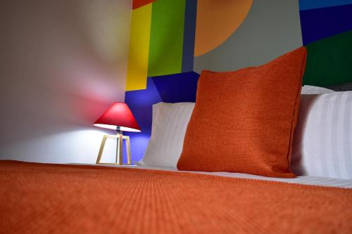 a bed with a colorful headboard and a red pillow at Tlaquepaque Pueblito in Guadalajara