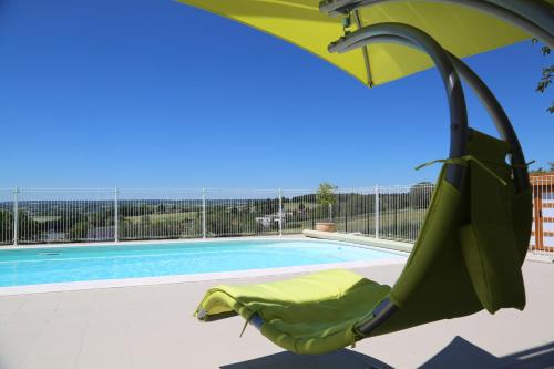 a green umbrella and a chair next to a swimming pool at GITE MONTGOLFIÈRE 4 PERSONNES in Châtellerault