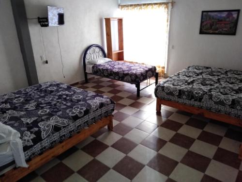 a bedroom with two beds and a checkered floor at Hotel Juarez in Cuernavaca