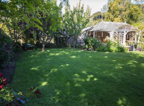a green yard with a gazebo in the background at The Summerhouse, Ideal Akaroa location. in Akaroa