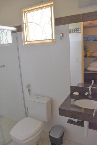 a bathroom with a toilet and a sink and a window at Chacara da Zelma in Capitólio
