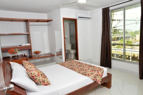 a bedroom with a bed and a large window at Hotel Canoa Inn in Caucasia