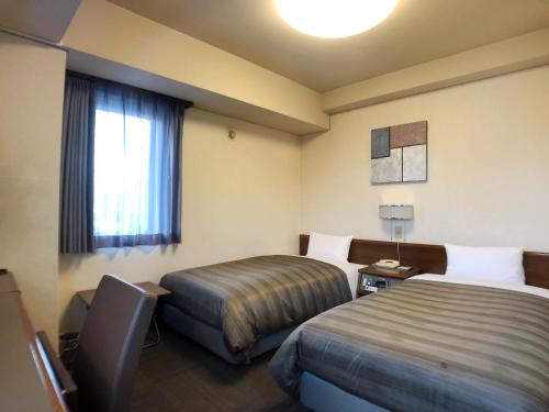 Habitación de hotel con 2 camas y ventana en HOTEL ROUTE-INN Ueda - Route 18 -, en Ueda