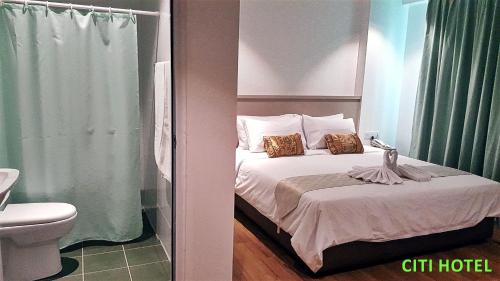 a small bedroom with a bed and a toilet at Citi Hotel in Miri