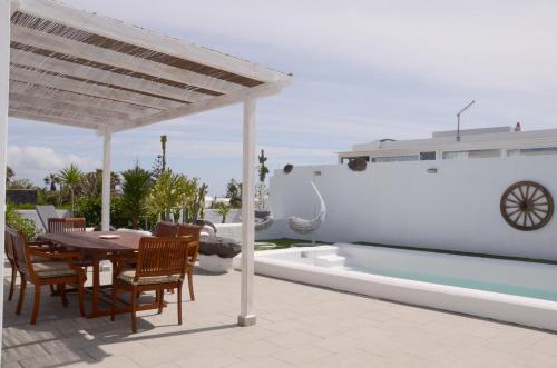 a patio with a table and chairs and a swimming pool at Villa Tranquilidad with amazing private terrace and heated pool in Charco del Palo