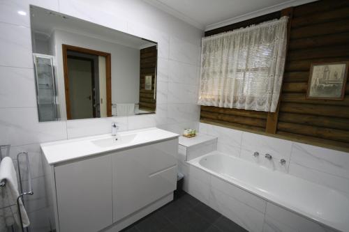 ein Badezimmer mit einem Waschbecken, einer Badewanne und einem Spiegel in der Unterkunft Halls Gap Log Cabins in Halls Gap