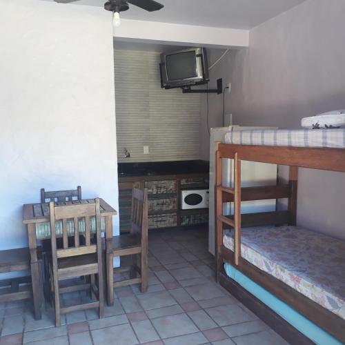 a room with two bunk beds and a table and a tv at Condominio Sargento Laranja in Garopaba