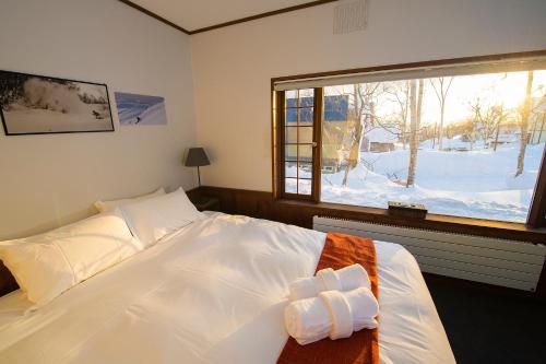 Lodge 401 Niseko Annupuri في نيسيكو: غرفة نوم مع سرير أبيض كبير مع نافذة