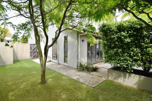 a house with a tree in the yard at Hagley Apartment - Christchurch Holiday Homes in Christchurch