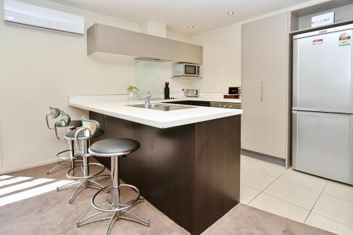 a kitchen with a sink and a refrigerator at Hagley Apartment - Christchurch Holiday Homes in Christchurch