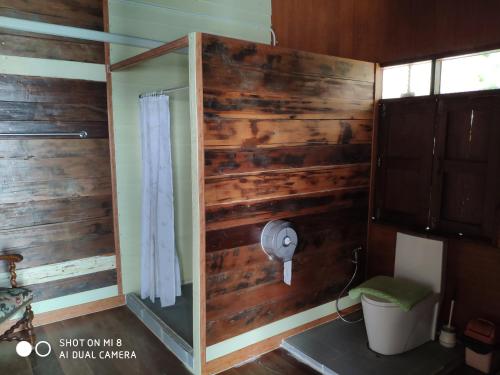 a bathroom with a wooden wall with a shower at homestay568 Branch 2 in Muang Suang