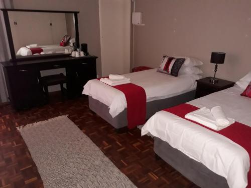 a room with two beds and a desk and a mirror at Caledon Overnight Rooms in Kimberley