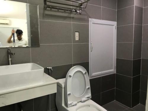 Ein Mann fotografiert ein Bad mit WC und Waschbecken in der Unterkunft Smiley Apartment 3 in Ho-Chi-Minh-Stadt