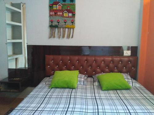 a bedroom with a bed with two green pillows at Bliss Guest House Assi Ghat in Varanasi