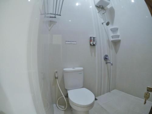 a white bathroom with a toilet and a shower at Griya Alsis Residence in Yogyakarta