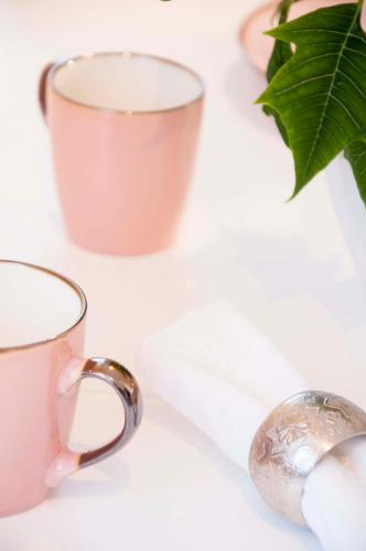two pink cups and a vase on a table at Charme apartment in Jelgava