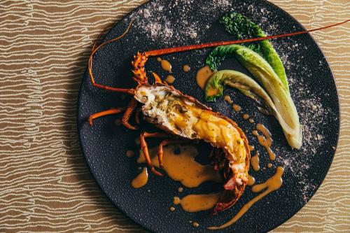 a black plate of food with a shrimp and vegetables at THE HIRAMATSU HOTELS & RESORTS KASHIKOJIMA in Shima