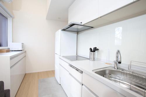 a kitchen with white cabinets and a sink at The Seasons Apartments Hakuba in Hakuba