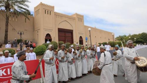 a group of men in white uniforms standing in front of a building at Nizwa Park House Apartment in Nizwa