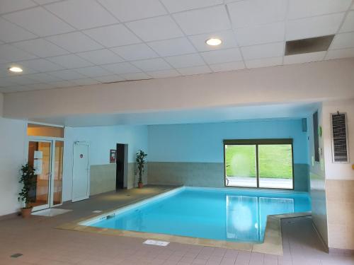 a large swimming pool in a room with a window at Studio dans résidence de tourisme*** in Giez
