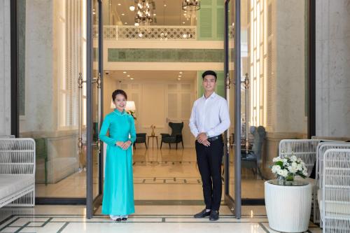 Un uomo e una donna in piedi su una porta di Minasi HanoiOi Hotel a Hanoi