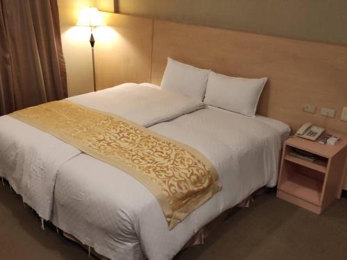 a bed in a hotel room with a phone on a table at 夏威夷酒店Melody Hawaii Hotel in Taitung City