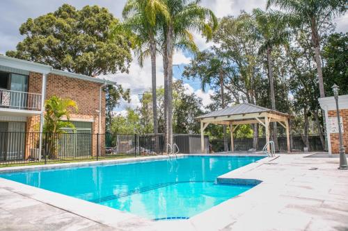 a swimming pool with a gazebo and palm trees at The Select Inn Gosford in Gosford