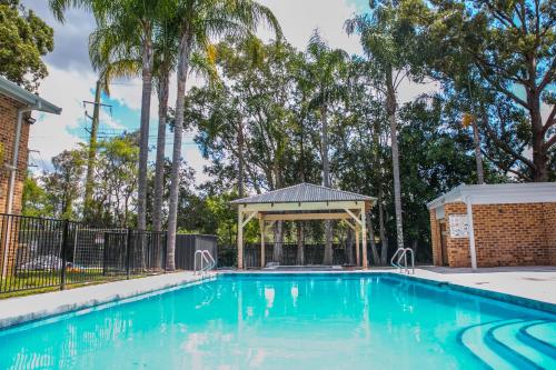 a swimming pool with a gazebo and trees at The Select Inn Gosford in Gosford