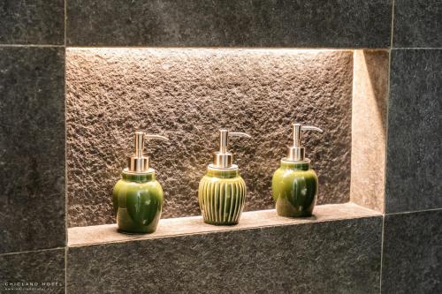 three green vases sitting on a shelf in a bathroom at Chicland Boutique Danang Beach Hotel in Da Nang