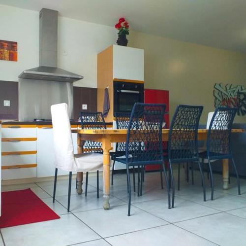a dining room table with chairs and a kitchen at Le Cascavelle in Cilaos