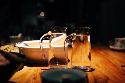 two glasses of beer sitting on a wooden table at The Twelve Manor•Terraces Lodge in Yuanyang