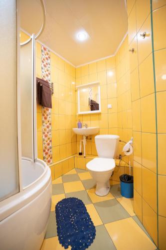 a yellow bathroom with a toilet and a sink at Silvana in Vilnius