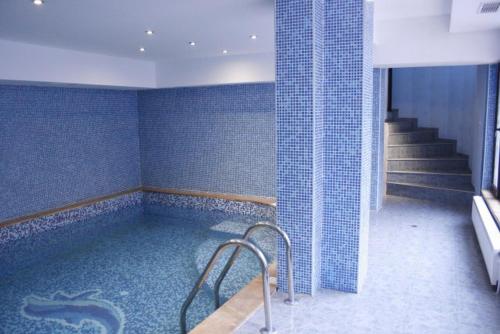 a bathroom with a jacuzzi tub with blue tiles at Family Hotel Ilinden in Shipkovo