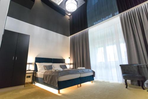 a bedroom with a bed and a chair and a window at Apart Hotel GOLDEN apartments in Košice