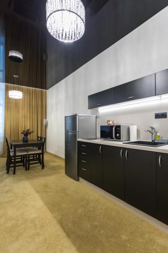 a kitchen with black cabinets and a table and a chandelier at Apart Hotel GOLDEN apartments in Košice