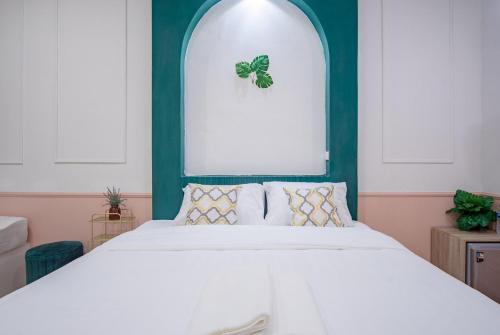 a bedroom with a white bed with a green wall at Isara Boutique Hotel and Cafe in Phuket Town