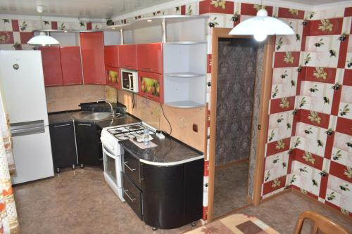 a kitchen with red cabinets and a white refrigerator at 2 комнатные апартаменты на Габдуллина 46а in Kokshetau