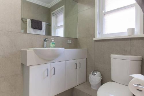 uma casa de banho com um lavatório branco e um WC. em M4 West Perth Studio Apartment near Kings Park em Perth