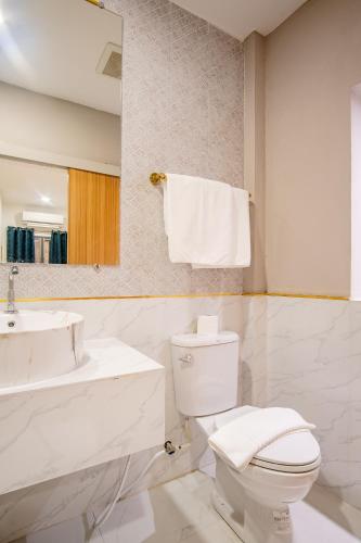 a white bathroom with a toilet and a sink at Isara Boutique Hotel and Cafe in Phuket Town