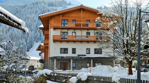 a large wooden building with a balcony in the snow at Herz3 Hotel Bar Restaurant Trattoria in Hollersbach im Pinzgau