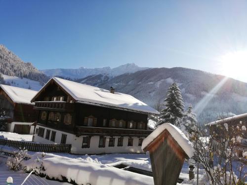 a building covered in snow with mountains in the background at Wurlerhof in Kals am Großglockner
