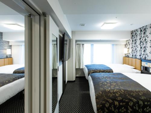 a hotel room with three beds and a window at APA Hotel Kyoto Ekihigashi in Kyoto