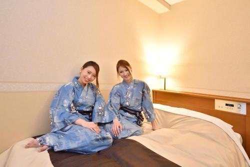 two women sitting on top of a bed at Hotel Seawave Beppu in Beppu